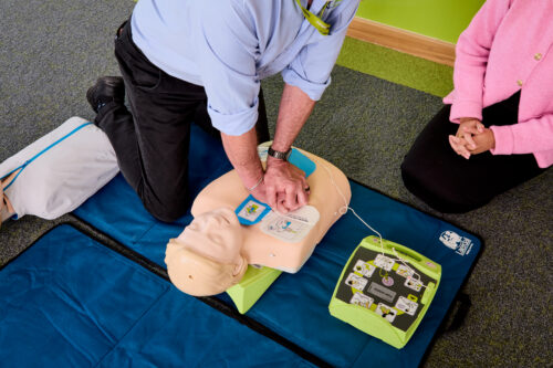 Image of one of our trainers on the Basic Life Support training course demonstrating a defibrillator on a dummy.
