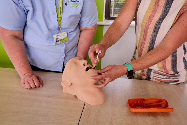 Image of an attendee on the Epilepsy Awareness with Rescue Medication Administration training course administering medication to a dummy while being observed by one of our trainers.
