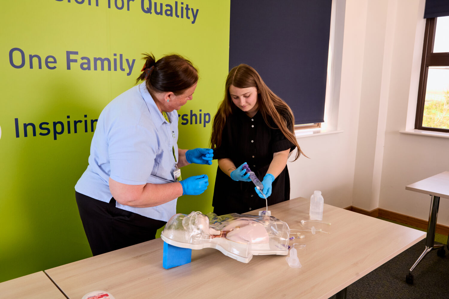 Image of an attendee of the Enteral Feeding training course using medical equipment while being observed by one of our trainers.