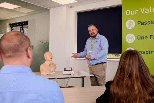 Image of one of our trainers on the Ventilation and Cough Assist Awareness training course showing dummy equipment to attendees.