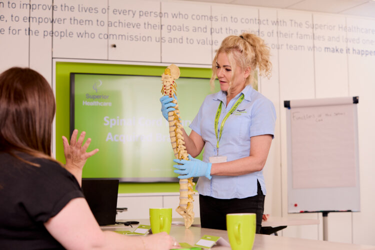 Image of one of our trainers on the Spinal Injury and Brain Injury Awareness training course demonstrating a model of the spine.